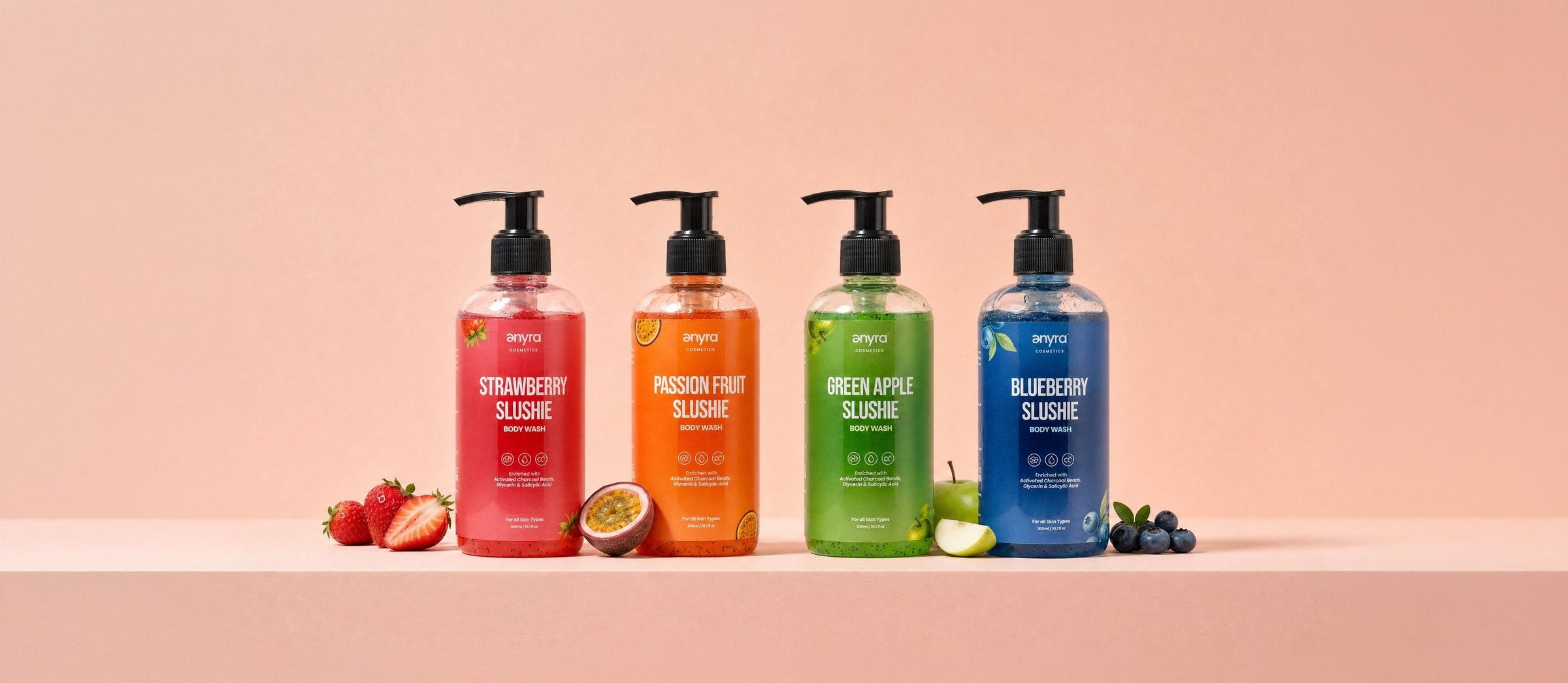 Strawberry, Passion Fruit, Green Apple and Blueberry Slushie body washes in a row on blush with their fruit